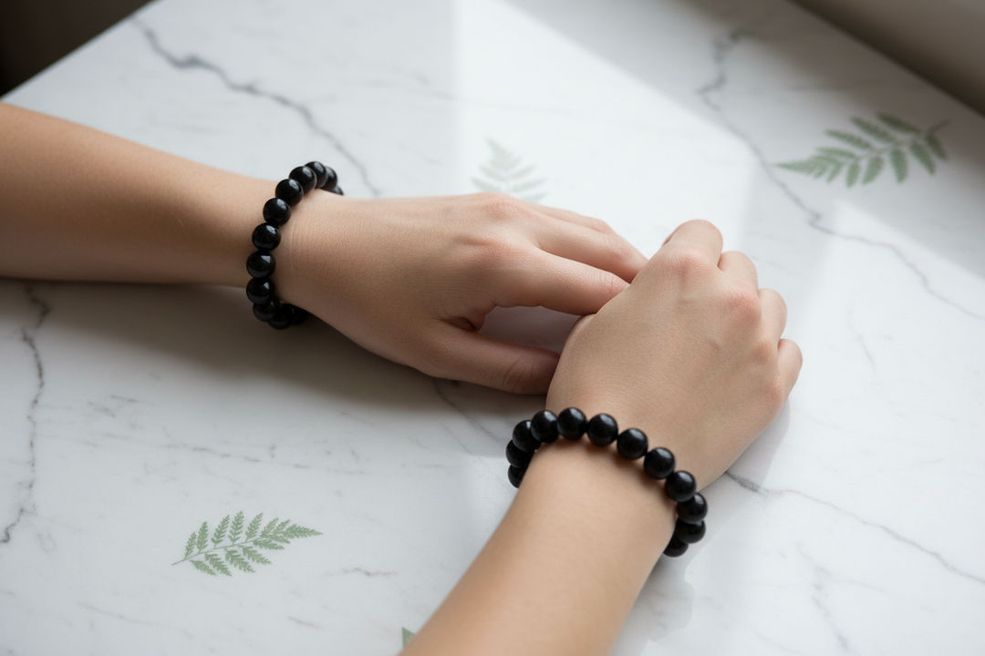 A premium genuine black obsidian bracelet worn correctly on the left wrist next to a luxury mechanical watch.