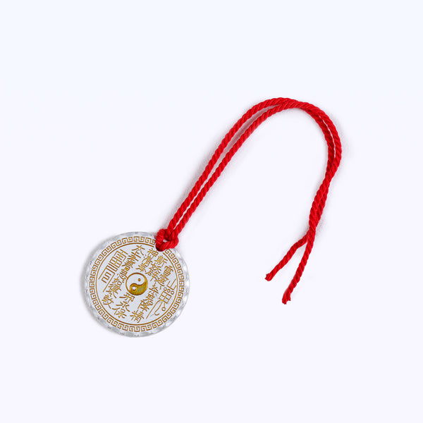 Front view studio product photograph of a premium mindfulness Feng Shui talisman charm made of polished silver-colored metal with a golden central Yin Yang symbol and a red braided cord on a clean white background.
