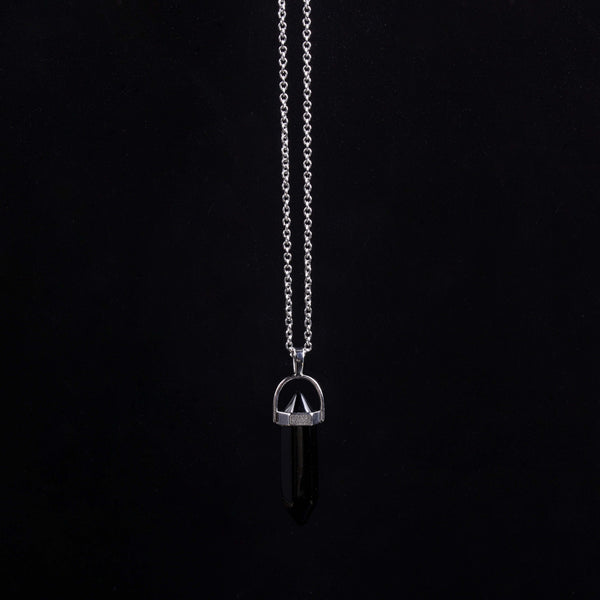 A moody, centered studio shot of the vertical black obsidian geometric point necklace suspended against a solid matte black background, emphasizing deep grounding and a luxury minimalist aesthetic.