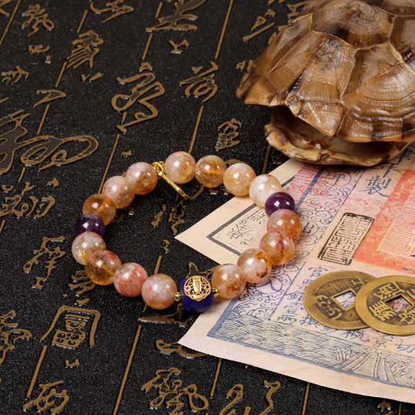 Side perspective view of the vibrant gold and blue gemstone protection bracelet laid over a traditional Chinese manuscript scroll, next to ancient coins and a textured turtle shell artifact.