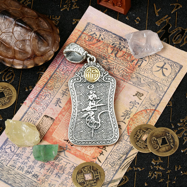 The back view of the sterling silver protection pendant resting on an old auspicious manuscript, showcasing the intricately engraved five-way prosperity symbols and traditional Hui-patterns.