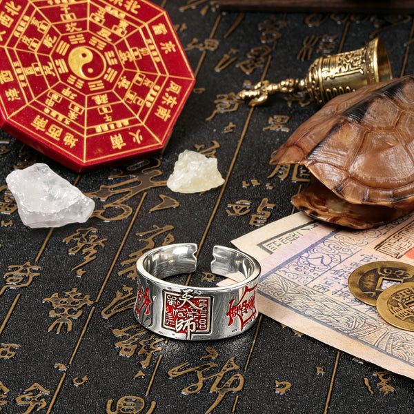 Top-down lifestyle view of the Taoist amulet silver ring arranged with a red Bagua clock, an antique bronze bell, a turtle shell, and raw quartz crystals for grounding field purification.